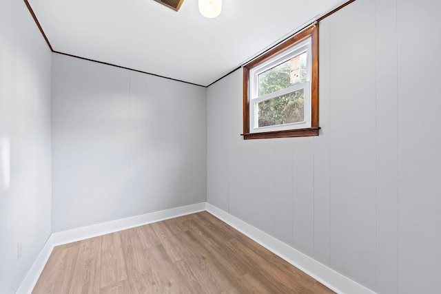 empty room featuring wood walls and light wood-type flooring