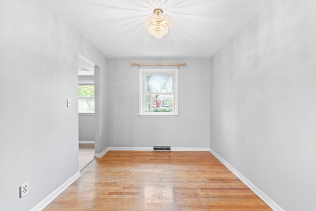 empty room with light hardwood / wood-style floors and a notable chandelier