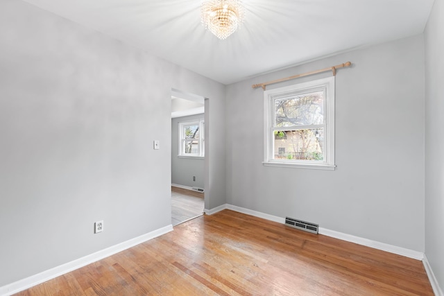 spare room featuring a chandelier and light wood-type flooring