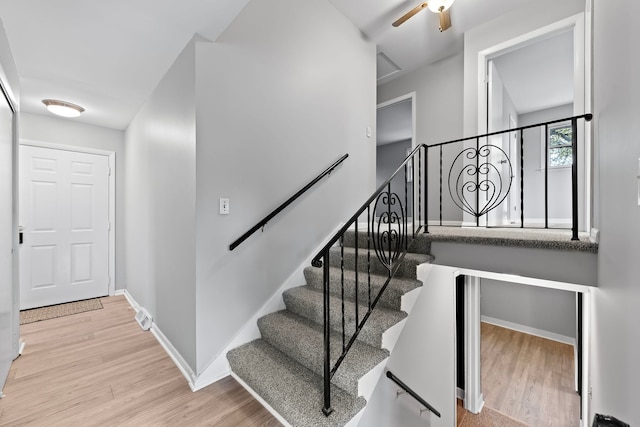 stairs with hardwood / wood-style floors and ceiling fan