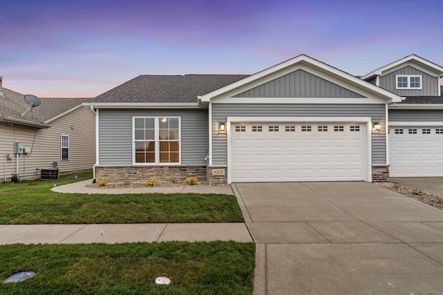 craftsman-style house featuring a lawn, central AC unit, and a garage