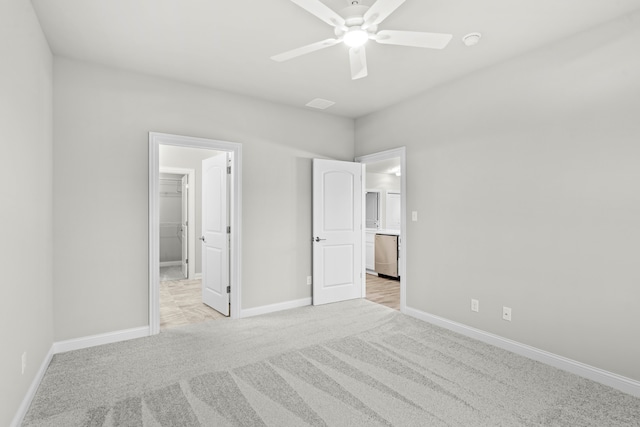 unfurnished bedroom featuring ceiling fan, a spacious closet, light carpet, and a closet