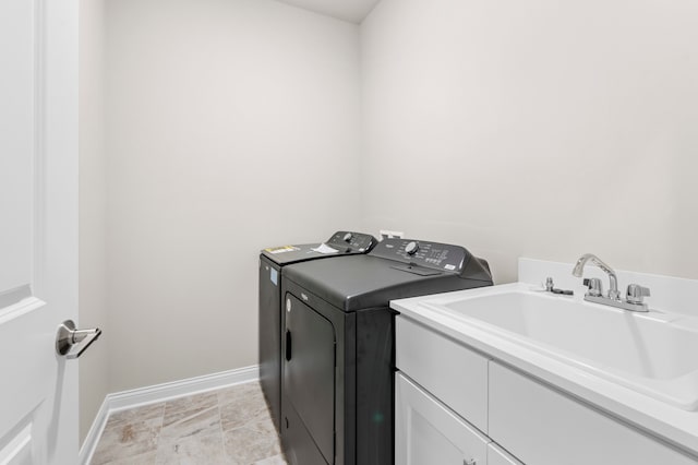 clothes washing area featuring sink, cabinets, and independent washer and dryer