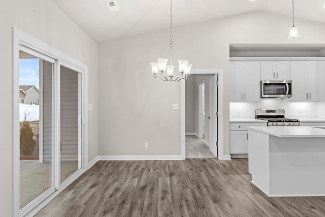 kitchen with light hardwood / wood-style floors, white cabinetry, appliances with stainless steel finishes, and vaulted ceiling