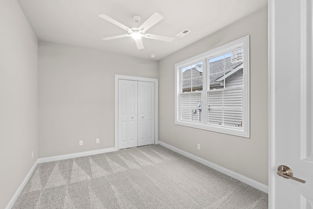 unfurnished bedroom with ceiling fan, light colored carpet, and a closet