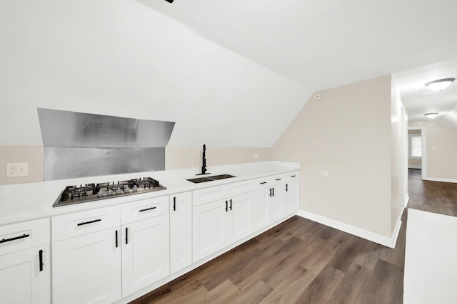 bar with stainless steel gas stovetop, dark hardwood / wood-style flooring, sink, and vaulted ceiling