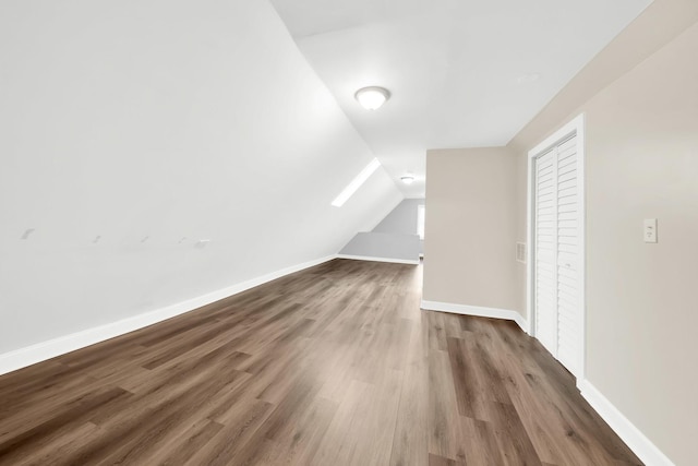 bonus room with dark hardwood / wood-style flooring and vaulted ceiling