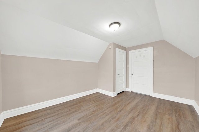 additional living space with hardwood / wood-style flooring and lofted ceiling