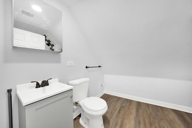 bathroom with vanity, toilet, wood-type flooring, and vaulted ceiling