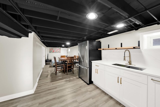 kitchen featuring stainless steel fridge, sink, white cabinets, and light hardwood / wood-style floors