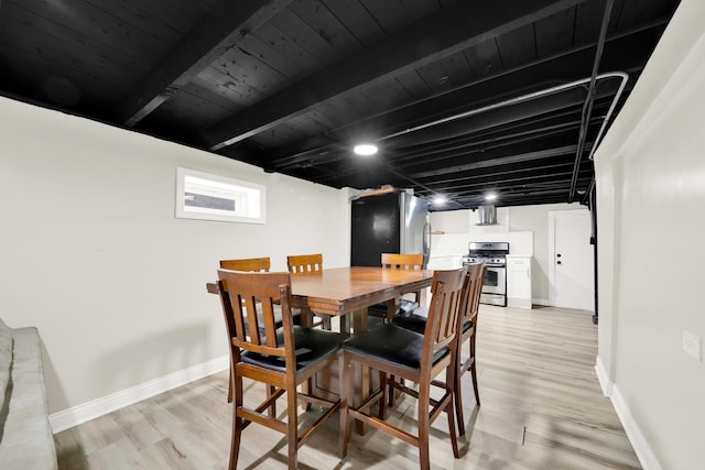 dining space featuring beamed ceiling and light hardwood / wood-style floors