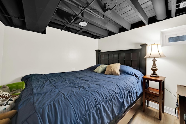 bedroom with hardwood / wood-style floors and beam ceiling