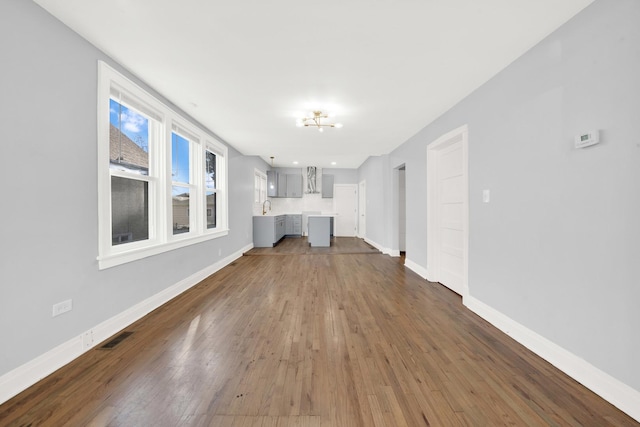 unfurnished living room featuring dark wood-type flooring and a notable chandelier