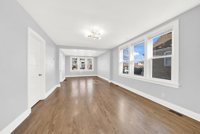 unfurnished living room with hardwood / wood-style floors and a notable chandelier