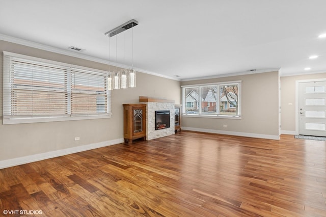 unfurnished living room featuring a fireplace, wood-type flooring, and ornamental molding