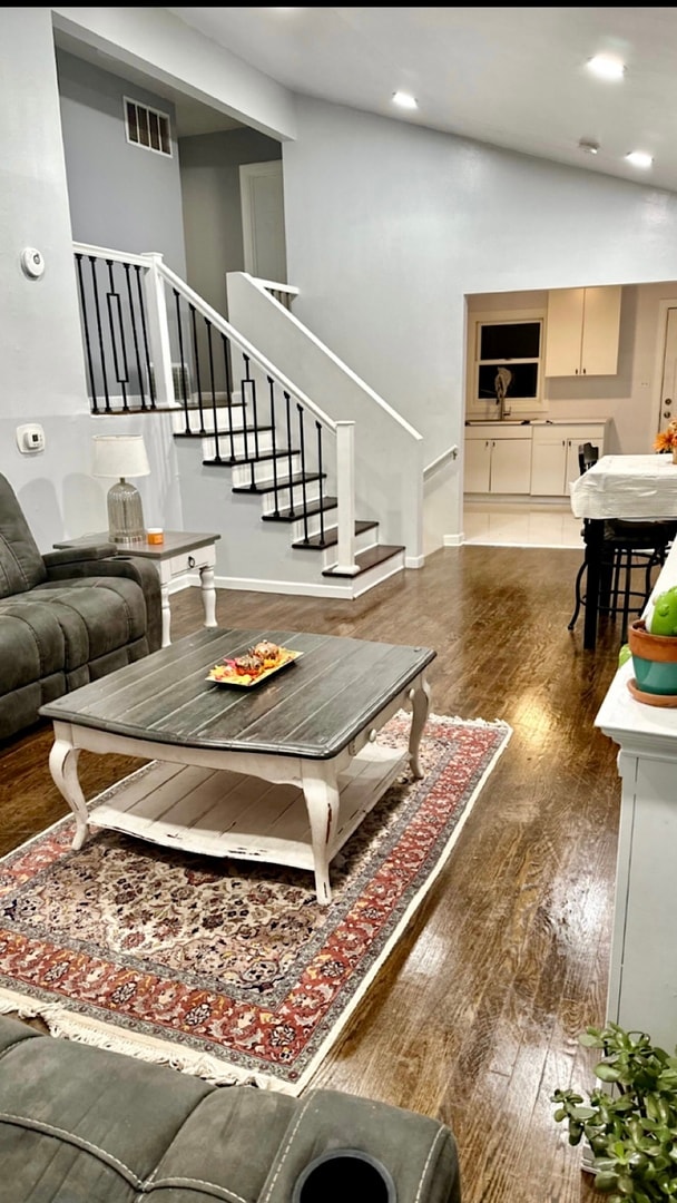 living room featuring dark hardwood / wood-style floors, high vaulted ceiling, and sink