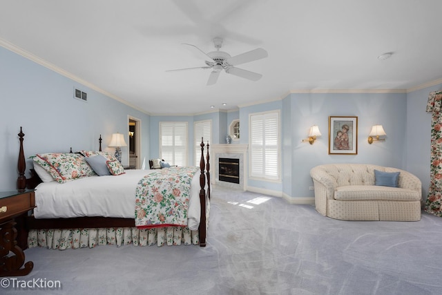 carpeted bedroom with ceiling fan, ornamental molding, and a tiled fireplace