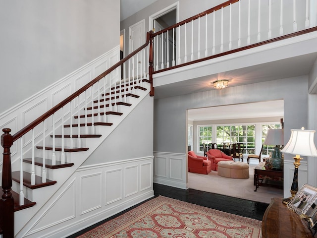 staircase with wood-type flooring and a high ceiling