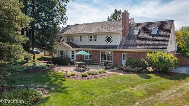 rear view of house featuring a lawn and a patio