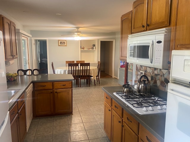 kitchen with kitchen peninsula, light tile patterned floors, white appliances, and ceiling fan