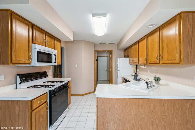 kitchen with kitchen peninsula, light tile patterned flooring, white appliances, and sink