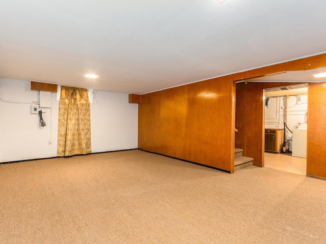 basement with washer / dryer, light carpet, and wooden walls