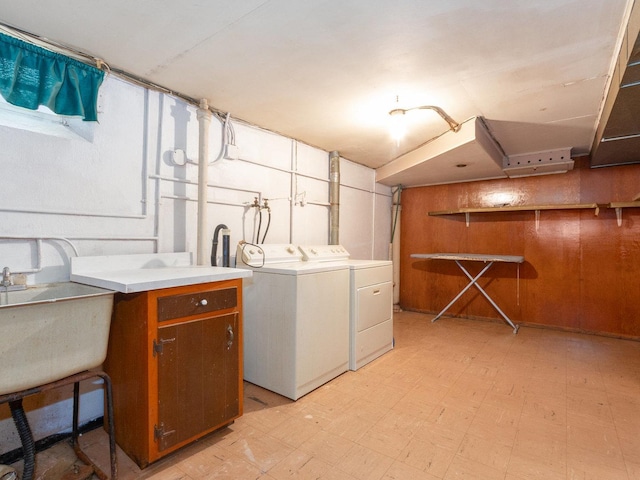 laundry area featuring separate washer and dryer, sink, and wooden walls