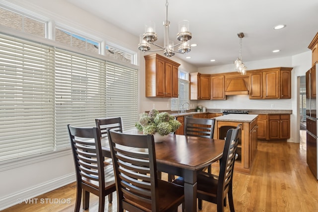 dining space with light wood-type flooring, sink, and a chandelier