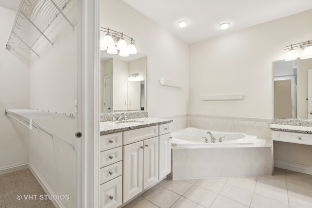 bathroom with tile patterned floors, vanity, and a relaxing tiled tub