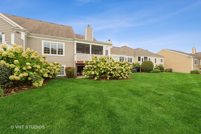 rear view of house with a sunroom and a yard