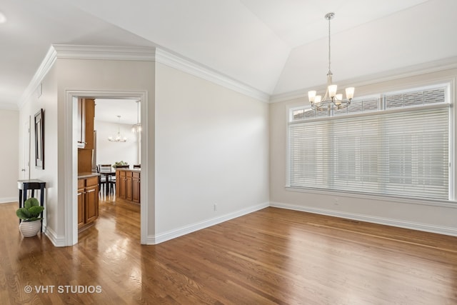 empty room with ornamental molding, a chandelier, lofted ceiling, and hardwood / wood-style flooring