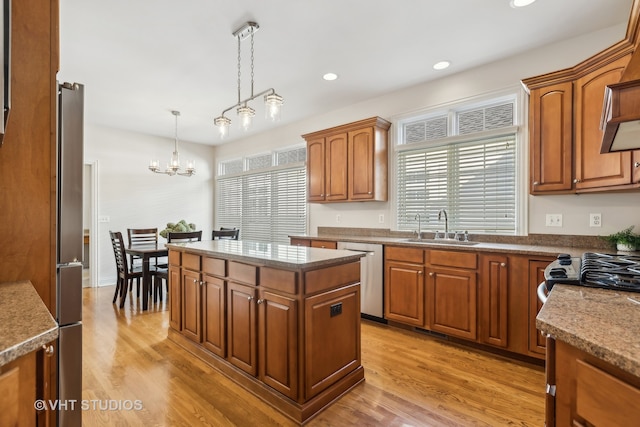 kitchen featuring a kitchen island, light wood-type flooring, decorative light fixtures, and appliances with stainless steel finishes