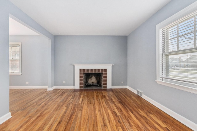 unfurnished living room featuring a fireplace, a healthy amount of sunlight, and hardwood / wood-style flooring