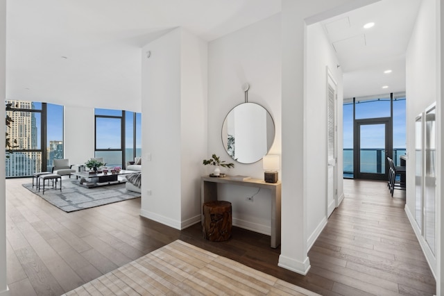 hall featuring hardwood / wood-style flooring, a water view, and a wall of windows