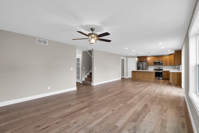 unfurnished living room with ceiling fan, sink, and light hardwood / wood-style floors