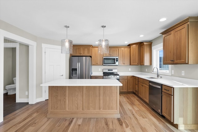 kitchen featuring pendant lighting, sink, light hardwood / wood-style flooring, a kitchen island, and stainless steel appliances