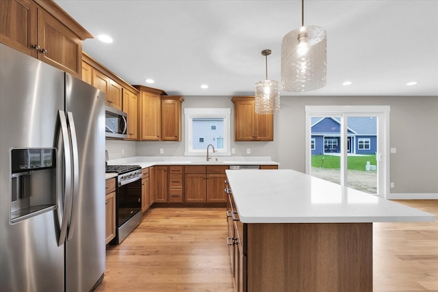 kitchen featuring pendant lighting, sink, light hardwood / wood-style flooring, a kitchen island, and stainless steel appliances