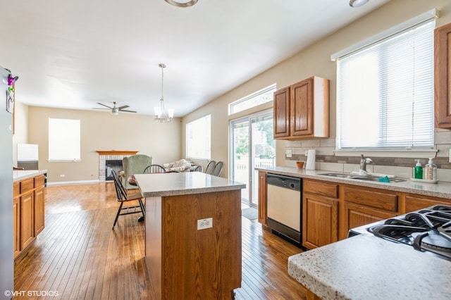 kitchen featuring backsplash, sink, pendant lighting, dishwasher, and a center island