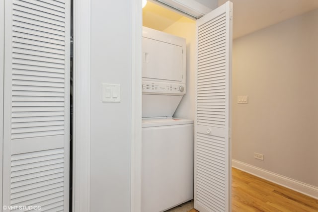 laundry room with stacked washer / drying machine and light wood-type flooring