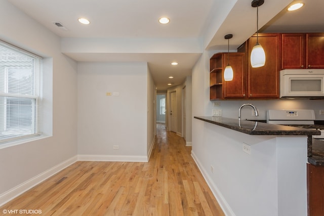 kitchen featuring sink, kitchen peninsula, dark stone countertops, light hardwood / wood-style floors, and decorative light fixtures