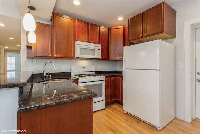 kitchen featuring kitchen peninsula, white appliances, sink, decorative light fixtures, and light hardwood / wood-style flooring