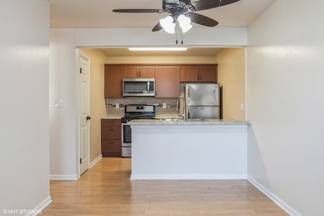 kitchen with light wood-type flooring, stainless steel appliances, tasteful backsplash, and sink