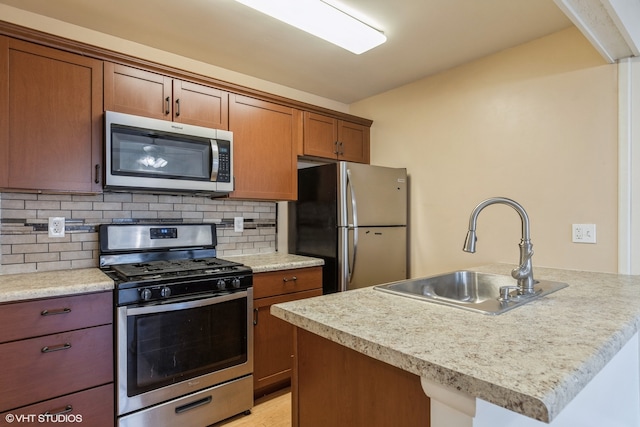 kitchen featuring backsplash, a kitchen island with sink, sink, and appliances with stainless steel finishes