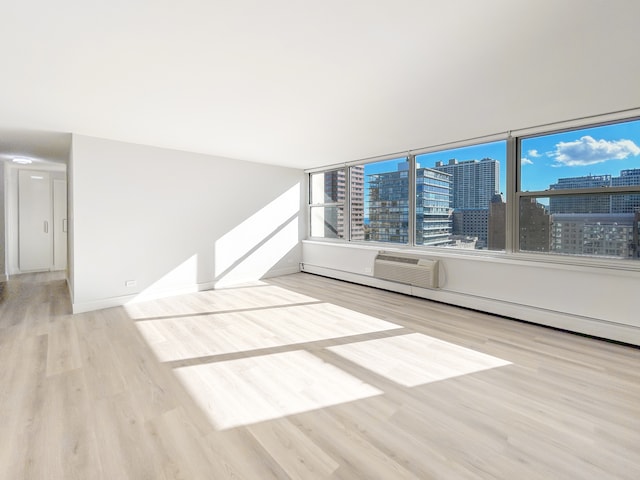 unfurnished room with light wood-type flooring and an AC wall unit