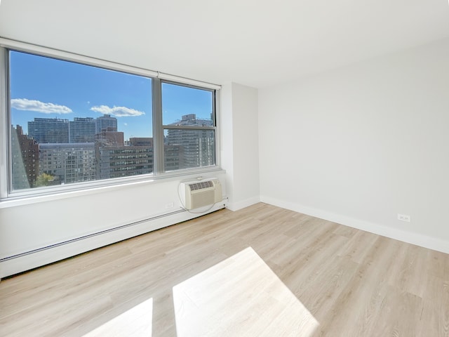 unfurnished room with light wood-type flooring, a wall unit AC, and a baseboard radiator