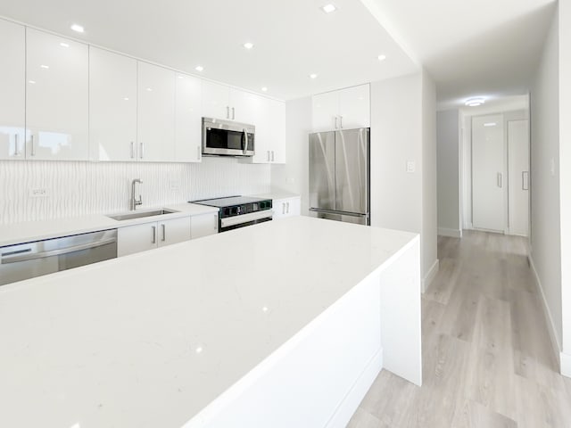 kitchen featuring white cabinets, sink, light wood-type flooring, and stainless steel appliances