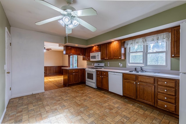 kitchen with kitchen peninsula, ceiling fan, white appliances, and sink