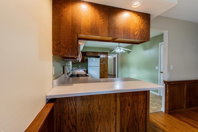 kitchen with kitchen peninsula, ceiling fan, hardwood / wood-style floors, range, and white fridge