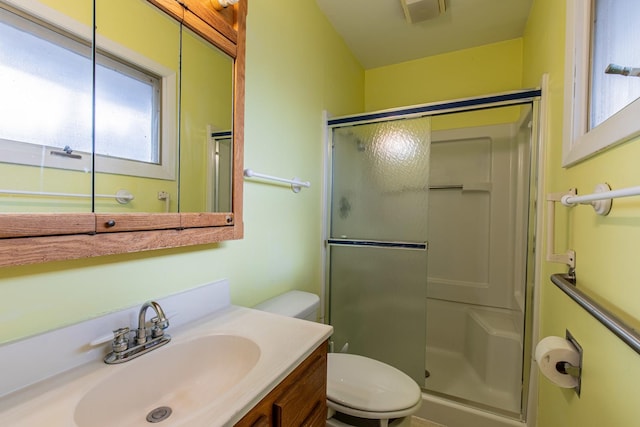 bathroom featuring vanity, a shower with shower door, and toilet