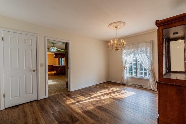 unfurnished dining area with ceiling fan with notable chandelier and dark wood-type flooring